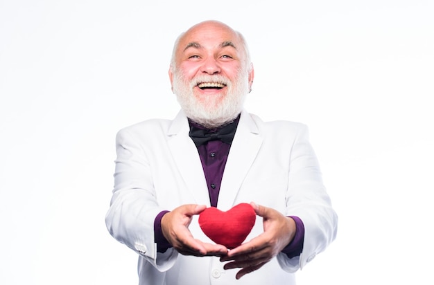 Cuidado de la salud Vida sana Hombre alegre con corazón de San Valentín Corazón y atención médica Diagnóstico y tratamiento Prevención de ataques cardíacos Hombre mayor con cabeza calva y barba sosteniendo un corazón de juguete rojo en las manos