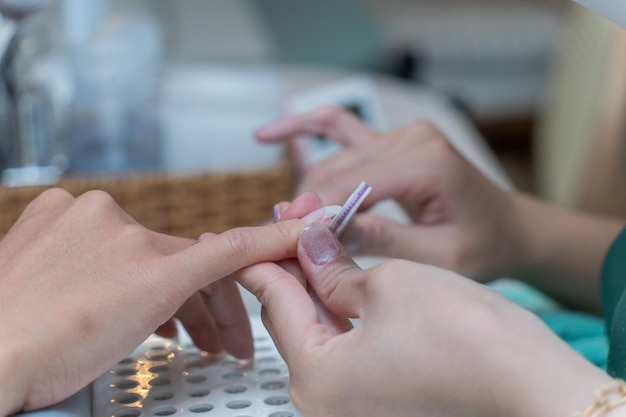 Cuidado de las uñas Closeup de manos femeninas limpiando uñas con limpiador profesional de uñas en un salón de uñas de belleza Detalles de manicura de uñas con un elemento de limpiador o pincel Proceso de cuidado de uñas hermosas para mujeres