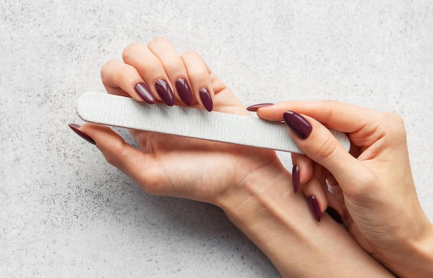 El cuidado de las uñas con una lima de uñas para lograr una manicura perfecta en casa en una encimera gris