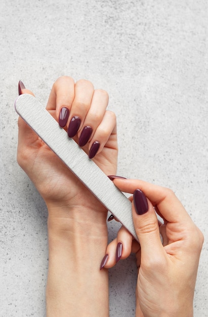 El cuidado de las uñas con una lima de uñas para lograr una manicura perfecta en casa en una encimera gris