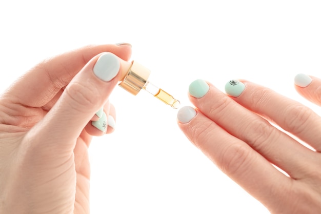 Cuidado de las uñas, una niña gotea aceite con vitaminas en las uñas