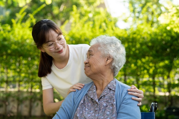 Cuidador ajuda e cuida de paciente idosa asiática sentada em cadeira de rodas na enfermaria do hospital de enfermagem conceito médico forte e saudável