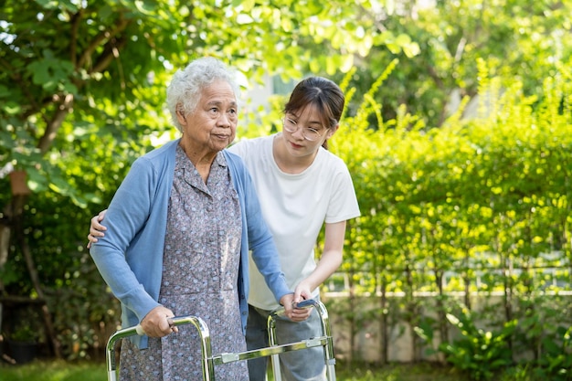Cuidador ajuda e cuidados As senhoras idosas asiáticas ou idosas usam andador com saúde forte enquanto caminham no parque em um feriado fresco feliz