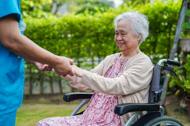 Cuidador ayuda a una anciana asiática con discapacidad en el concepto médico del hospital de enfermería