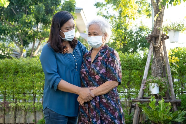 El cuidador ayuda a una anciana asiática mientras camina feliz en el parque natural