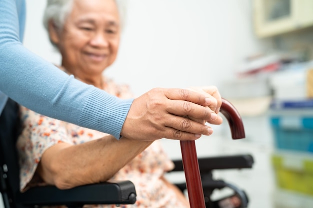El cuidador ayuda a una anciana asiática a una paciente anciana con cariño y empatía en el hospital de enfermería con un concepto médico fuerte y saludable