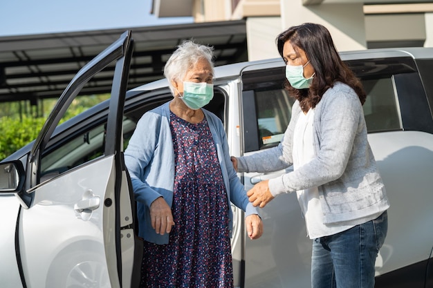 El cuidador ayuda y apoya a una anciana o anciana asiática que camina con un andador y se prepara para llegar a su automóvil concepto médico fuerte y saludable