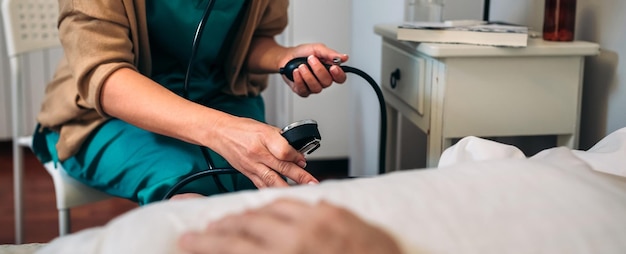 Cuidador feminino verificando a pressão arterial para uma mulher idosa em casa