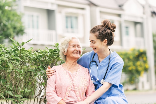 Cuidador con mujer anciana asiática al aire libre