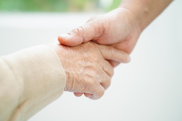 Cuidador tomados de la mano Asia anciana paciente ayuda y cuidado en el hospital