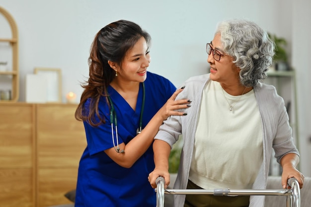 Foto cuidadora sorridente ajudando mulher idosa andando com andador assistência reabilitação e conceito de saúde