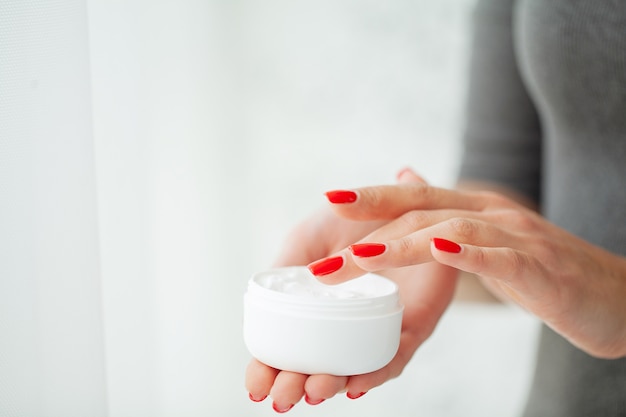 Cuidados com a pele das mãos. close-up de mãos femininas, segurando o tubo de creme, mãos de mulher bonita com unhas de manicure natural, aplicar creme para as mãos cosmético na pele macia e sedosa e saudável