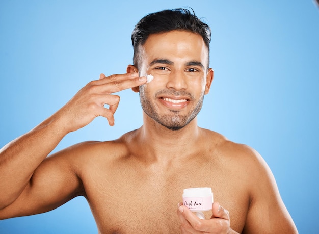 Foto cuidados com a pele de beleza e homem com creme no rosto para uma pele saudável no fundo azul do estúdio loção hidratante e jovem modelo do canadá hidratam com creme para cuidar do corpo pele bonita ou brilhante