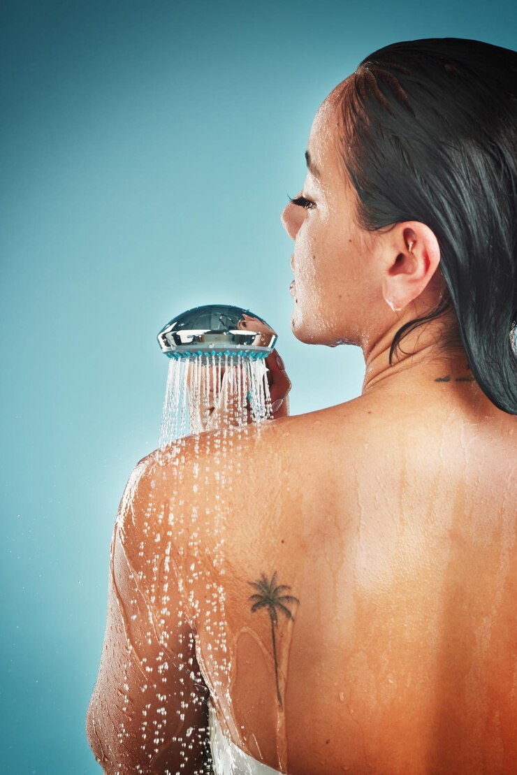 Foto cuidados com a pele de beleza e mulher em um chuveiro para cuidar da higiene e do cabelo contra um fundo azul limpeza de água e garota em respingos de água para rotina de bem-estar e amor próprio da pele e mimos de estúdio