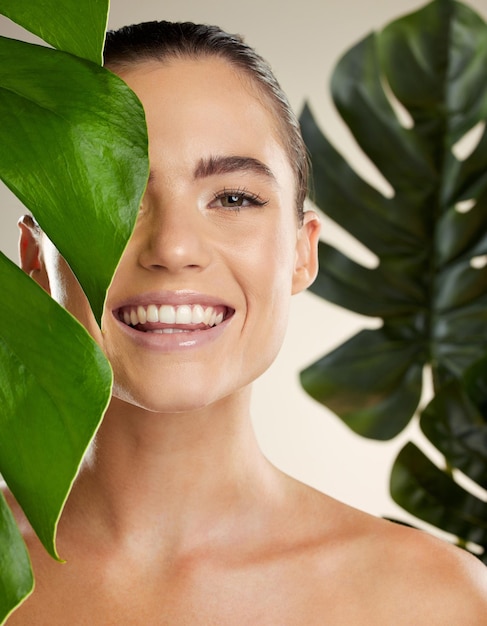 Cuidados com a pele de beleza e retrato de mulher com planta verde para produto cosmético de dermatologia de pele natural Rosto feliz de modelo estético em estúdio para brilho sustentável ou maquiagem para saúde e bem-estar