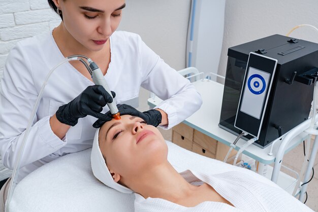 Cuidados com a pele do rosto. Closeup de mulher rosto limpeza na clínica de cosmetologia, aspiração