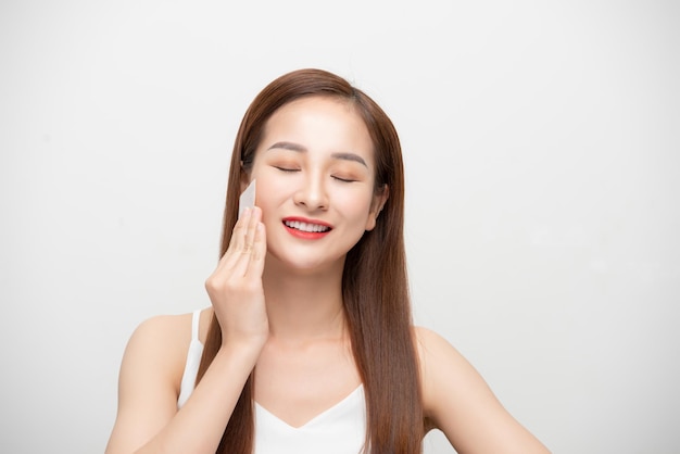 Cuidados com a pele do rosto mulher asiática sorridente usando retrato de papel absorvente de óleo facial