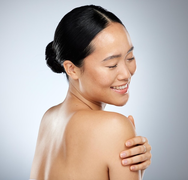 Cuidados com a pele e cuidados com o corpo com uma mulher asiática modelo em estúdio em um fundo cinza para bem-estar natural Tratamento cosmético e cuidados com a pele com uma mulher atraente posando para promover um produto