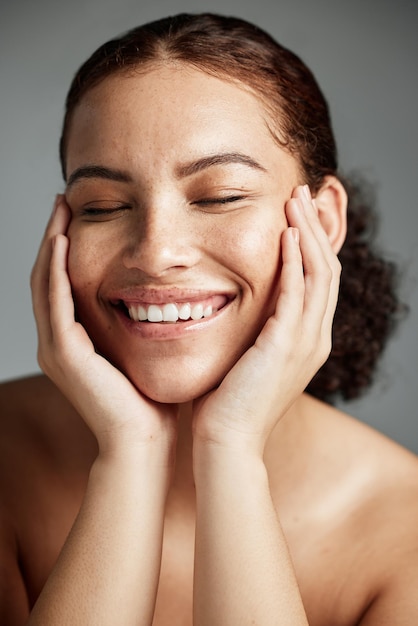 Foto cuidados com a pele e maquiagem com uma modelo negra em estúdio em um fundo cinza para promover cuidados naturais bem-estar facial e maquiagem com uma jovem atraente feliz com seu produto cosmético