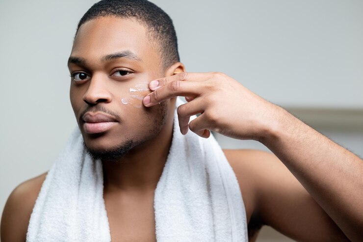 Foto cuidados com a pele masculina tratamento facial hidratante da pele confiante homem africano sem camisa com toalha branca ap