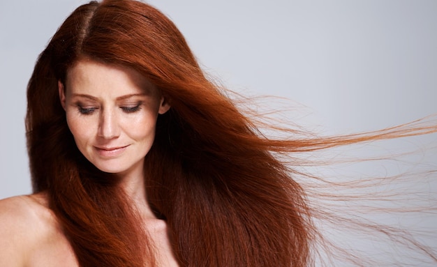 Cuidados com o cabelo cabeça vermelha e mulher com vento para tratamento de queratina bem-estar e beleza em fundo branco Cabeleireiro de salão e rosto de modelo feminino com brilho penteado saudável e natural em estúdio