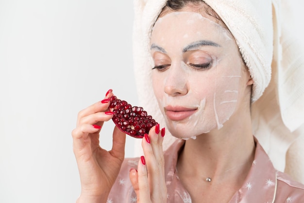 Cuidados com o rosto e tratamentos de beleza Mulher com uma máscara de romã hidratante de folha no rosto isolado no fundo branco