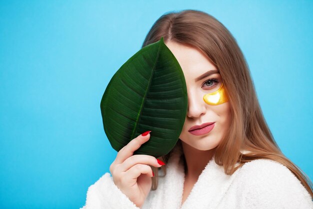 Cuidados com o rosto, jovem segurando uma folha verde perto da saúde da pele facial.