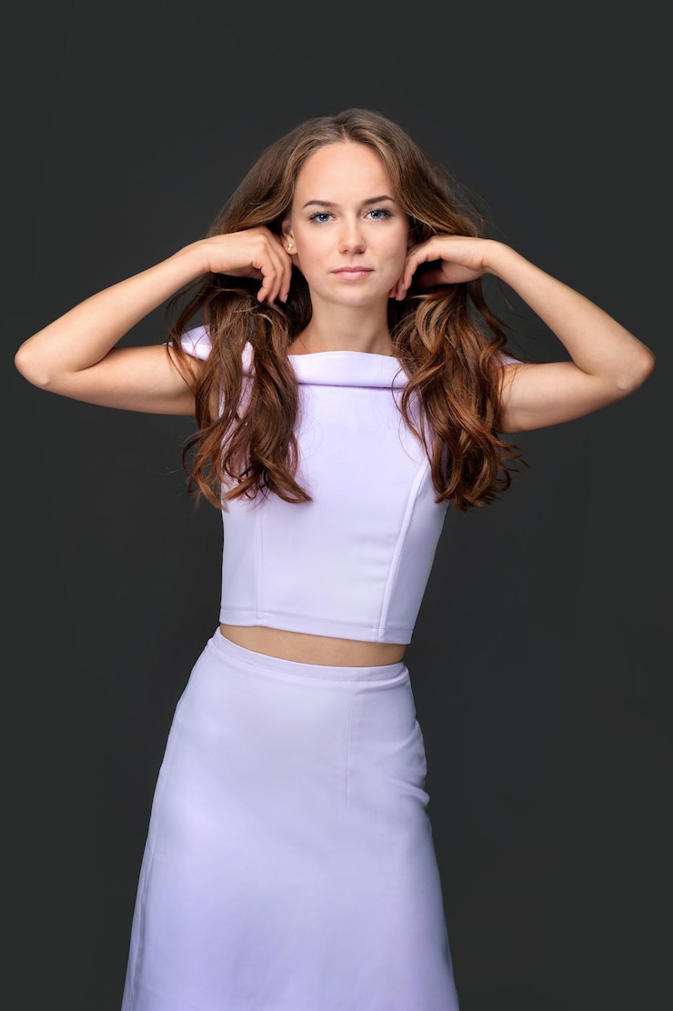 Foto cuidados com os cabelos e moda beleza feminina uma jovem mantém as mãos atrás da cabeça enquanto fica de pé com um vestido lilás olhando para a câmera