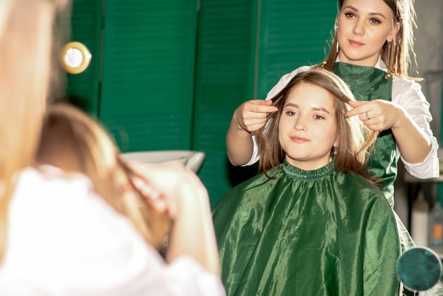 Cuidados com os cabelos profissionais linda jovem morena caucasiana com cabelos longos recebendo penteados em um salão de beleza