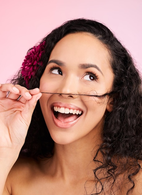 Foto cuidados de cabelo bem-estar e jovem mulher em um estúdio com curls naturais bonitos e longos sorriso feliz e modelo feminino do méxico com um tratamento de salão brilhante penteado isolado por um fundo rosa