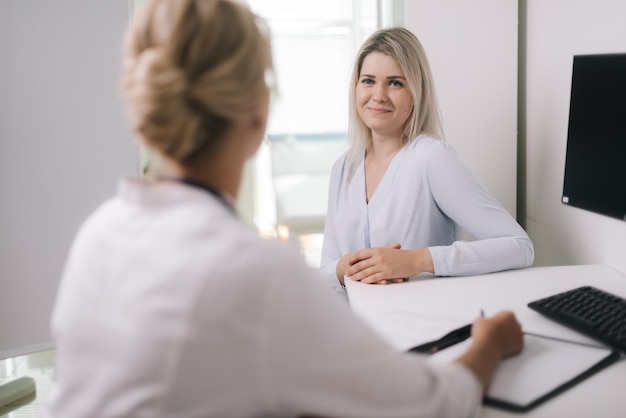 Cuidados de saúde e conceito médico - médico com paciente jovem no hospital, na consulta médica. Mulher terapeuta sentada à mesa e faz perguntas ao paciente