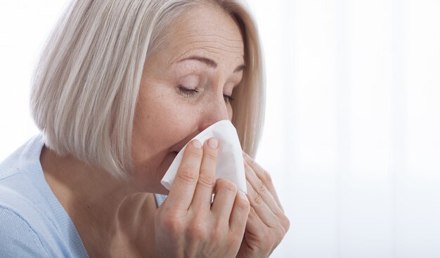 Cuidados de saúde, frio, alergia e mulher doente assoar o nariz escorrendo em papel absorvente.