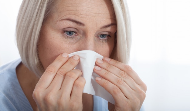 Cuidados de saúde, frio, alergia e mulher doente assoar o nariz escorrendo em papel absorvente.