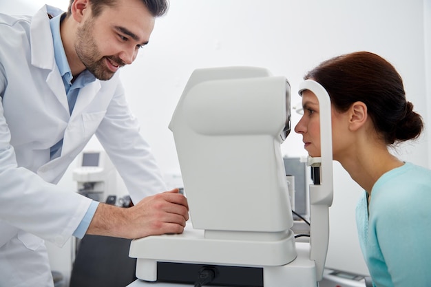 Foto cuidados de saúde, medicina, pessoas, visão e conceito de tecnologia - optometrista com tonômetro sem contato, verificando a pressão intra-ocular do paciente na clínica oftalmológica ou loja de ótica