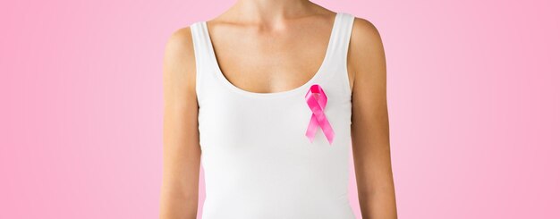 cuidados de saúde, pessoas, oncologia e conceito de medicina - close-up da mulher na camisa branca com fita rosa de conscientização do câncer