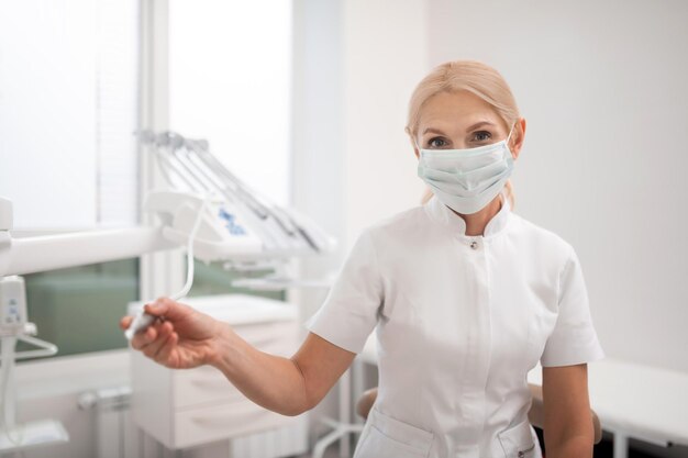 Cuidadosa dentista sosteniendo una de sus herramientas antes de perforar un diente de su paciente