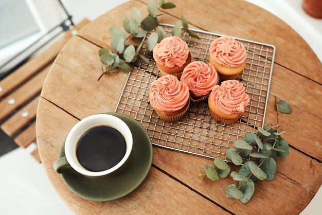 Cuidadosamente arreglado y listo para el blog Toma de ángulo alto de pastelitos recién horneados en una bandeja de metal y una taza de café en una mesa en el interior