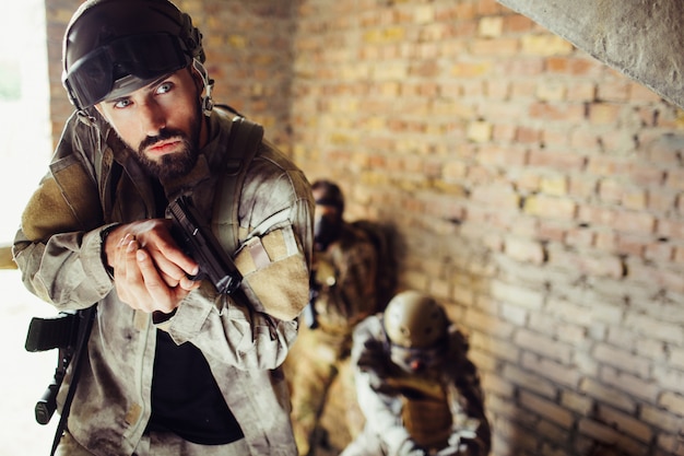 Cuidadoso soldado está de pie con sus combates en una habitación.