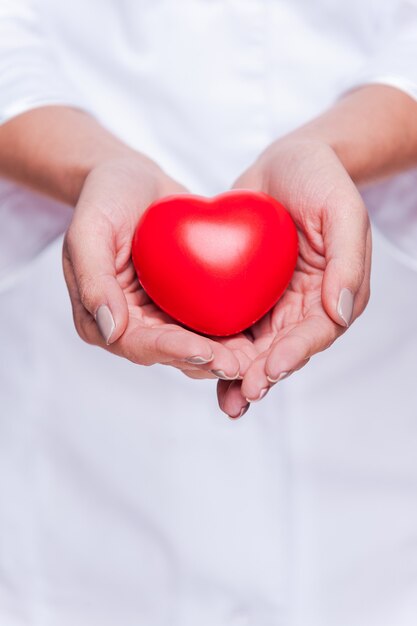 Cuidando bien tu corazón. Primer plano de la doctora en uniforme blanco con apoyo de corazón