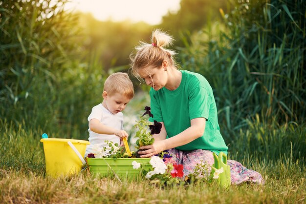 Cuidando da natureza. Mãe e filho que plantam plântulas no chão na atribuição na margem do rio. Conceito de botânica e ecologia.