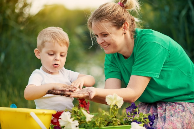 Cuidando da natureza. Mãe e filho que plantam plântulas no chão na atribuição na margem do rio. Conceito de botânica e ecologia.