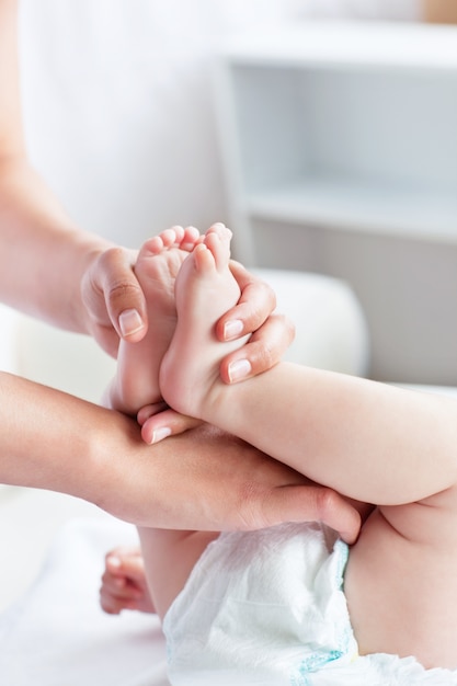 Cuidando joven madre cambiando el pañal de su bebé