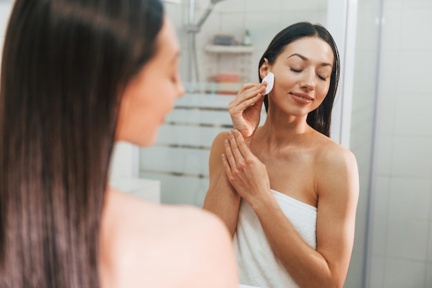 Cuidando su piel La mujer caucásica joven con forma de cuerpo delgado está en el interior durante el día