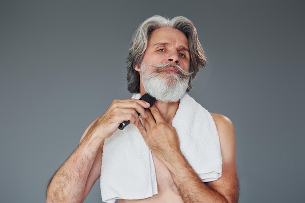 Cuidar da barba Homem moderno e elegante com cabelos grisalhos está dentro de casa