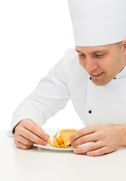 culinária, profissão, alta cozinha, comida e conceito de pessoas - close-up do feliz chef masculino cozinheiro decorando a sobremesa