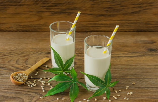 Óculos com folhas de cannabis e glúten vegan à base de ervas Cannabis e leite sem lactose na mesa de madeira.