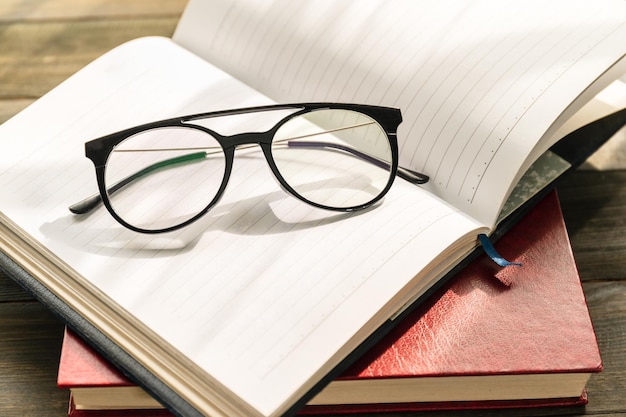 Óculos de leitura colocados em um livro aberto sobre a mesa de madeira