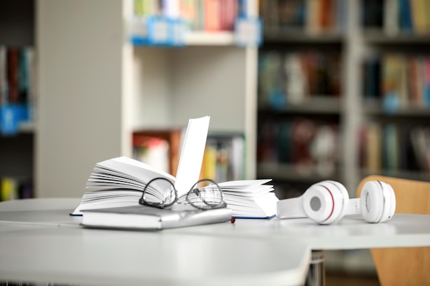 Óculos de livros e fones de ouvido na mesa na biblioteca