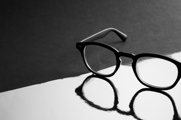 Óculos de moda preto na superfície reflexiva