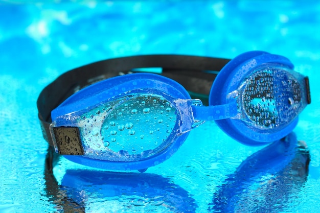 Óculos de natação azuis com gotas no fundo do mar azul